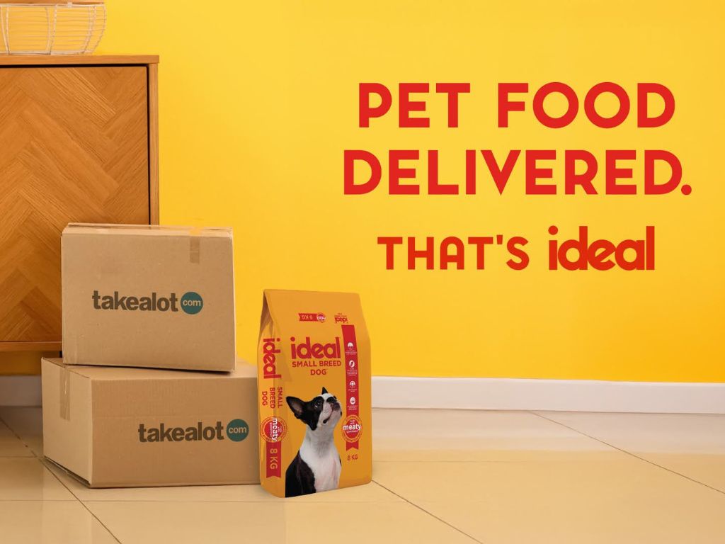 Takealot delivery boxes next to a bag of Ideal Small Breed Dog food with the headline "Pet Food Delivered. That’s Ideal" on a bright yellow wall.